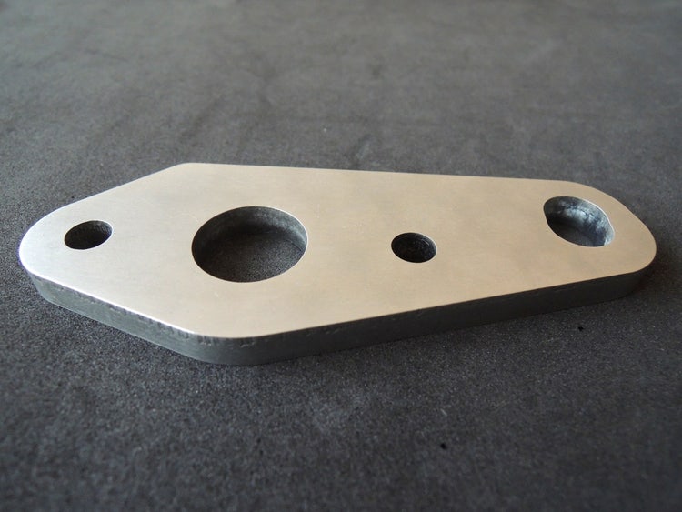 Metal plate with three holes on a gray background
